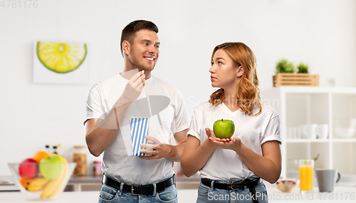 Image of couple in white t-shirts with popcorn and apple