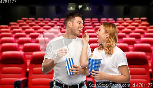 Image of happy couple in t-shirts eating popcorn at cinema