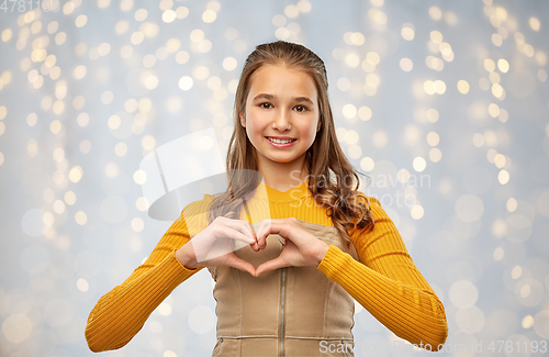 Image of smiling teenage girl making hand heart