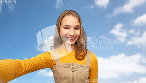 Image of happy teenage girl taking selfie over sky