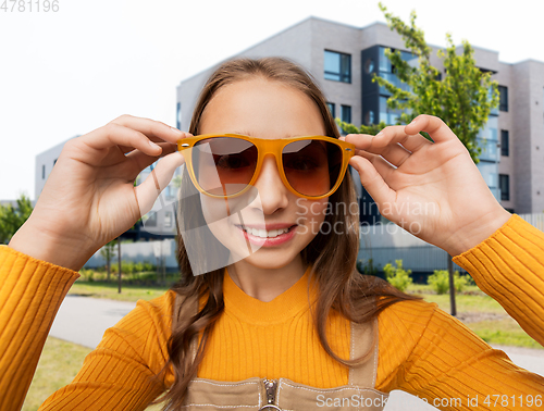 Image of smiling teenage girl in sunglasses on city street