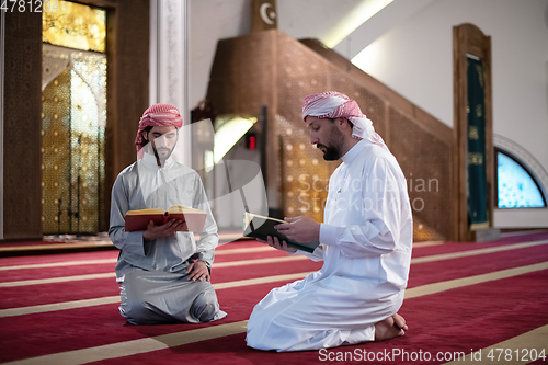 Image of two muslim people in mosque reading quran together concept of islamic education