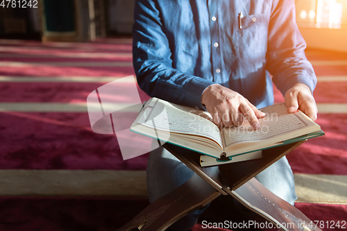 Image of muslim man praying Allah alone inside the mosque and reading islamic holly book