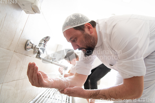 Image of a group of Muslims take ablution for prayer. Islamic religious rite