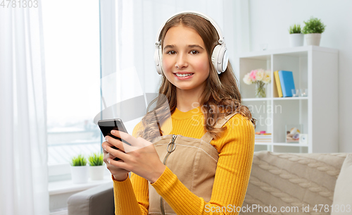 Image of teenage girl in headphones with smartphone at home