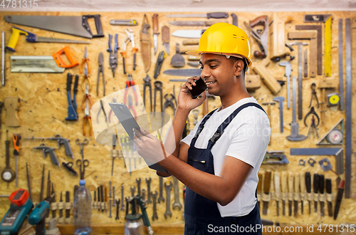 Image of indian builder with clipboard calling on cellphone
