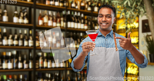 Image of indian barman with glass of cocktail at bar