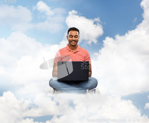 Image of happy indian man with laptop computer in clouds