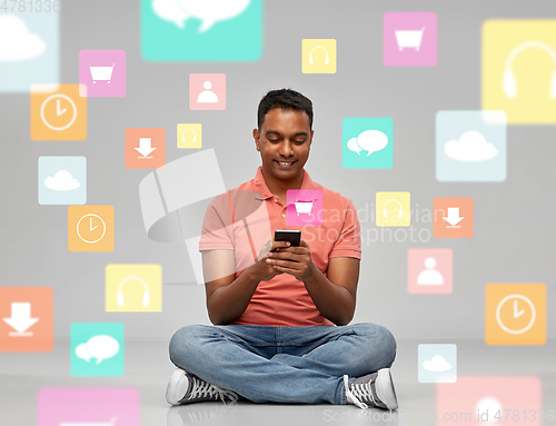 Image of happy indian man using smartphone over app icons