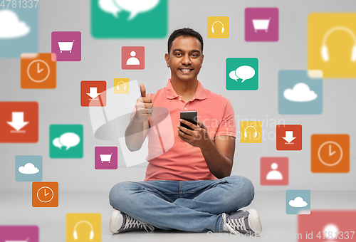 Image of happy indian man with smartphone showing thumbs up