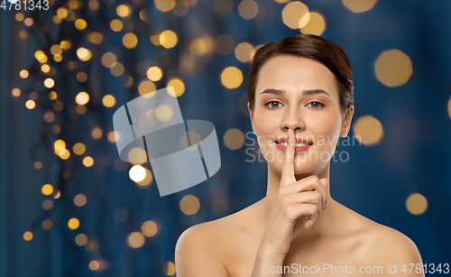 Image of beautiful young woman holding finger on lips