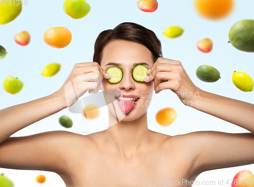 Image of beautiful woman making eye mask of cucumbers