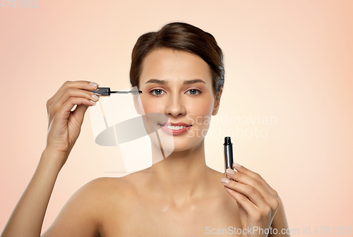 Image of beautiful woman applying mascara