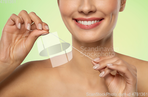 Image of smiling woman with dental floss cleaning teeth