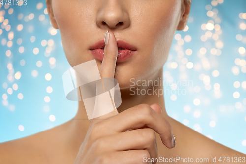 Image of beautiful young woman holding finger on lips