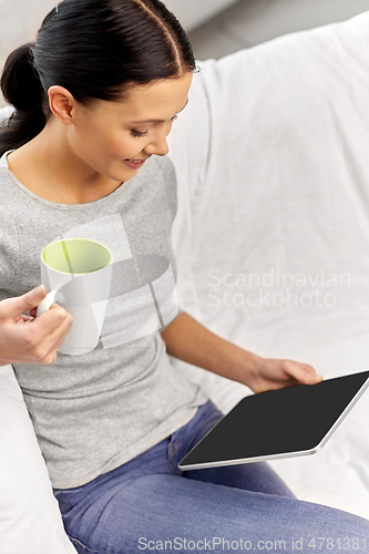 Image of young woman with tablet computer and mug at home