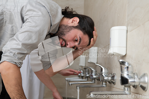 Image of a group of Muslims take ablution for prayer. Islamic religious rite