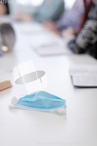 Image of Closeup of protective medical face mask at desk on business meeting
