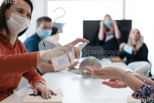 Image of new normal businesspeople on meeting using antibacterial hand sanitizer