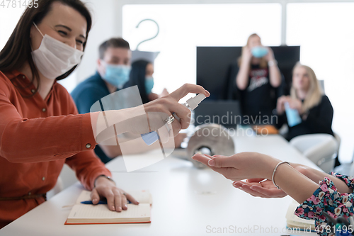 Image of new normal businesspeople on meeting using antibacterial hand sanitizer