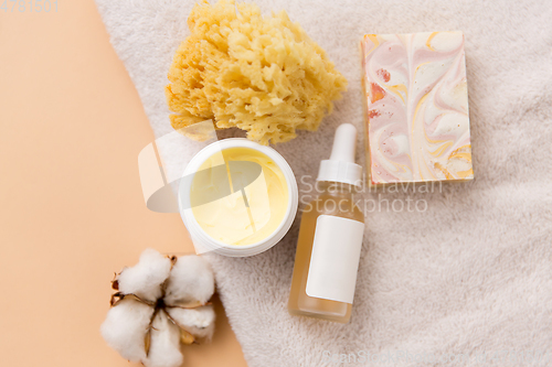 Image of body butter, essential oil, sponge on bath towel