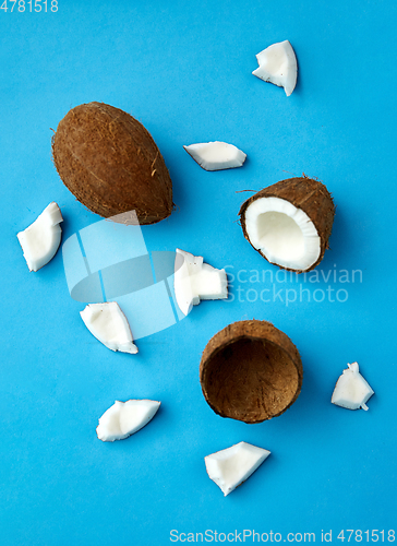 Image of whole and cracked coconut on blue background