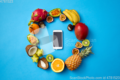 Image of exotic fruits around smartphone on blue background