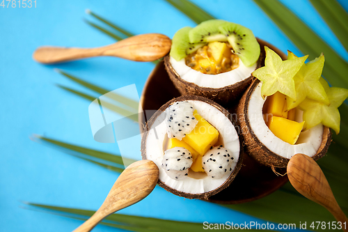 Image of mix of exotic fruits in coconut shells with spoons