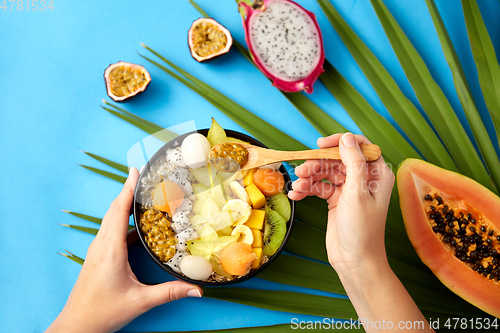 Image of hands with mix of exotic fruits and wooden spoon