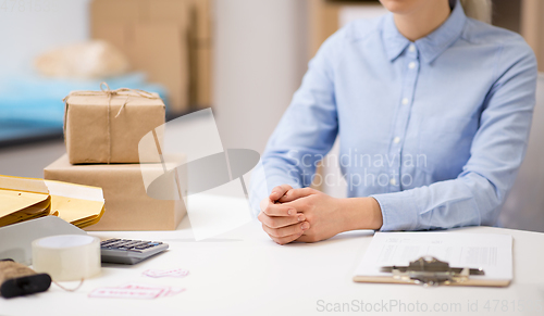 Image of woman with clipboard and parcels at post office