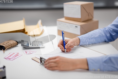 Image of hands with clipboard and parcels at post office