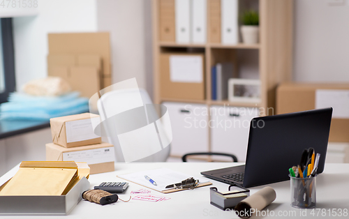 Image of laptop and parcels on table at post office