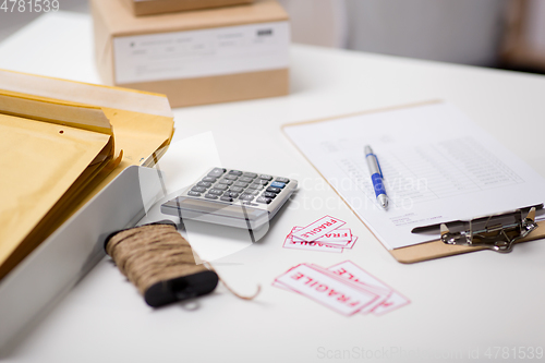 Image of calculator, clipboard and envelopes at post office