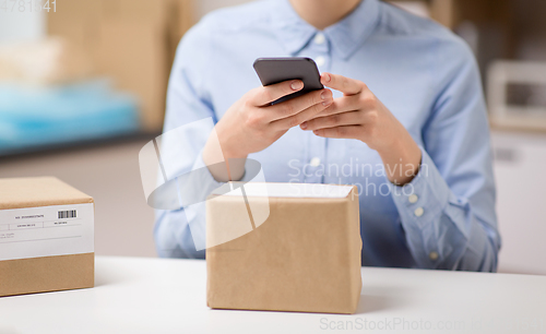 Image of woman with smartphone and parcels at post office