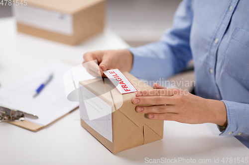 Image of woman sticking fragile mark to parcel box