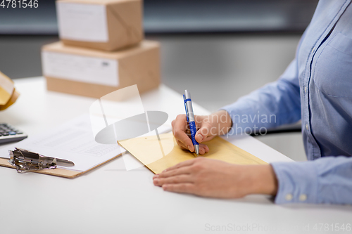 Image of woman writing on parcel envelope at post office