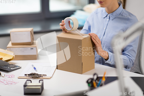 Image of woman packing parcel box with adhesive tape