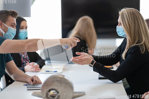 Image of new normal businesspeople on meeting using antibacterial hand sanitizer