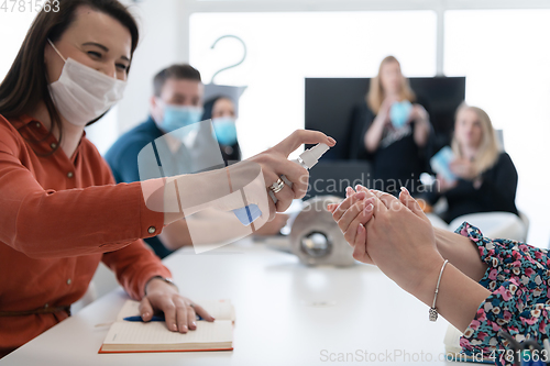 Image of new normal businesspeople on meeting using antibacterial hand sanitizer