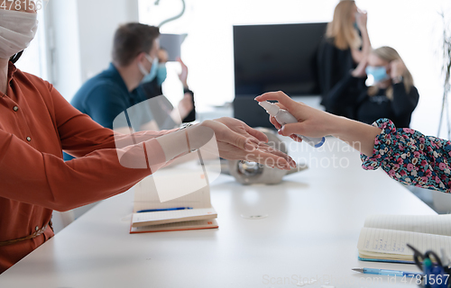 Image of new normal businesspeople on meeting using antibacterial hand sanitizer