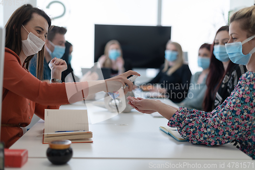 Image of new normal businesspeople on meeting using antibacterial hand sanitizer