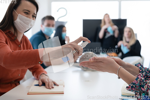 Image of new normal businesspeople on meeting using antibacterial hand sanitizer
