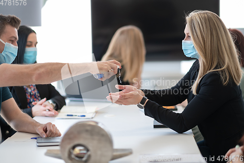 Image of new normal businesspeople on meeting using antibacterial hand sanitizer