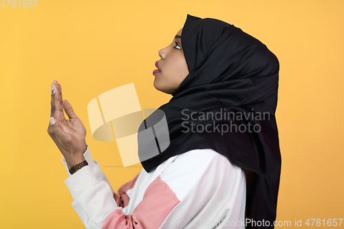 Image of african muslim woman wearing hijab and traditional muslim clothes posing in front of green background