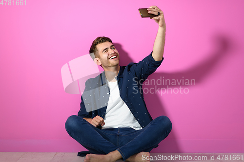 Image of man sitting on the floor of the house and using the phone