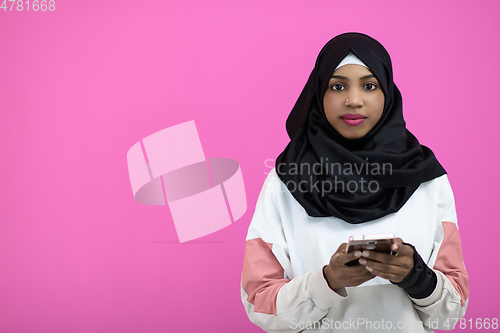 Image of afro woman uses a cell phone in front of a pink background