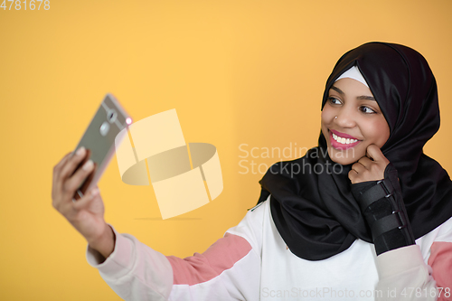 Image of african muslim woman with a beautiful smile takes a selfie with a cell phone