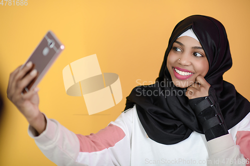 Image of african muslim woman with a beautiful smile takes a selfie with a cell phone