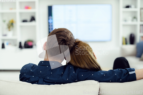 Image of young couple watching tv at home in bright living room