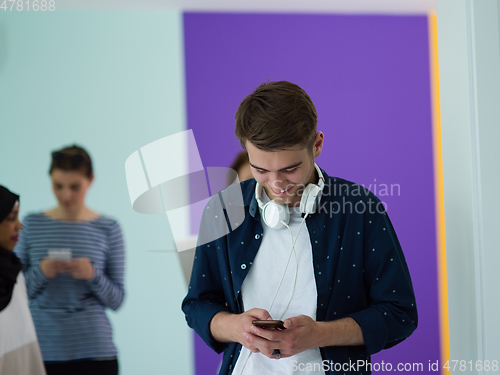 Image of group of diverse teenagers use mobile devices while posing for studio photo